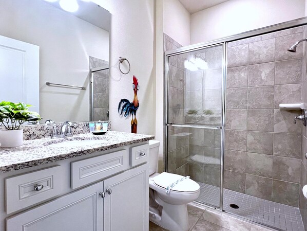 A bathroom with a shower, toilet, sink, and a decorative rooster.