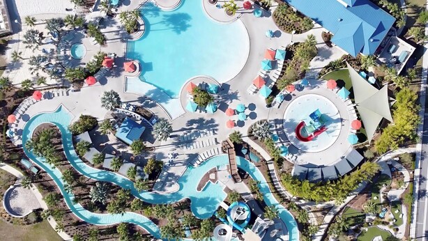 Un resort con una gran piscina central, varias piscinas más pequeñas y un tobogán de agua.