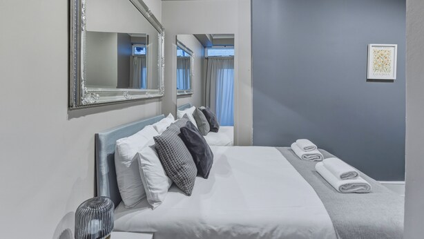 Een hotelkamer met een groot bed, een spiegel, een nachtkastje en een kunstwerk aan de muur.