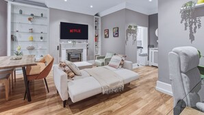 Een moderne woonkamer met een bank, een salontafel en een televisie waarop 'NETFLIX' wordt weergegeven.