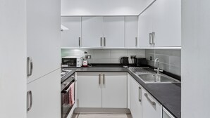 Een moderne keuken met witte kasten, roestvrijstalen apparatuur en een zwart aanrecht.