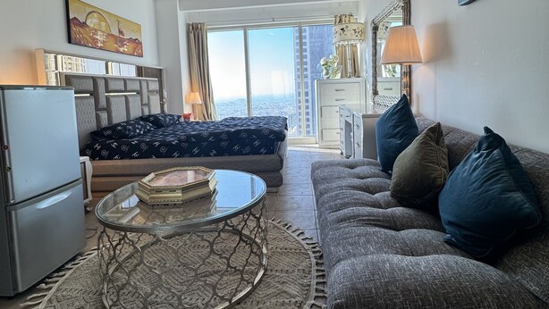 Una sala de estar moderna con un sofá, una mesa de centro de vidrio y una zona de comedor con una lámpara.