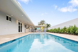 A swimming pool with a slide, a covered area with seating, and a view of the sky. - The Spectacular Miami Resort/5 Bedrooms/Htd Pool/MiniGolf/Playground/Baby Items (Miami)