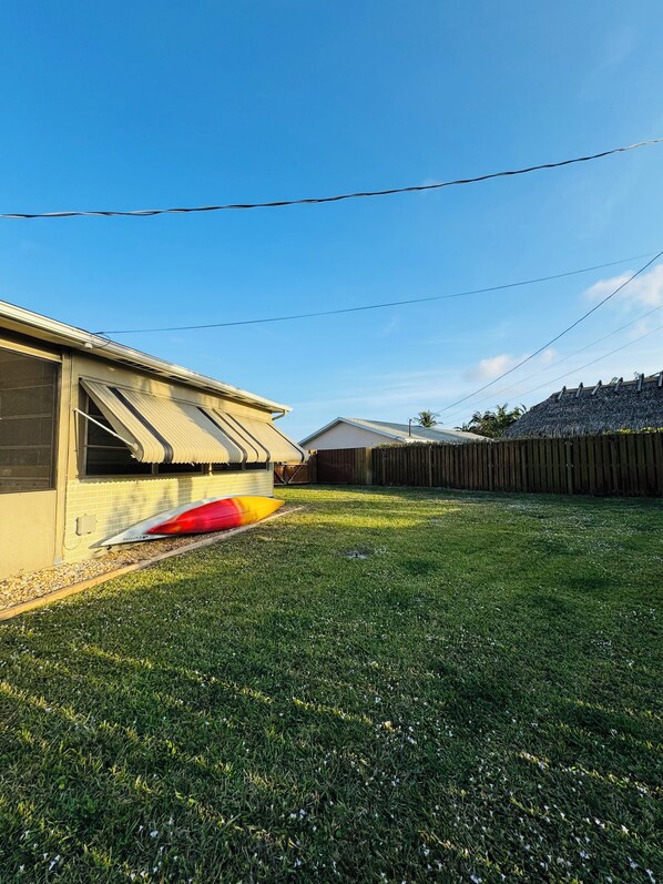 A residential backyard with a house, a wooden fence, and a grassy lawn.