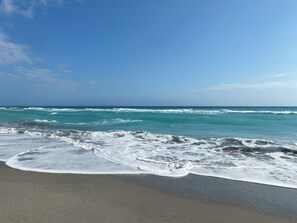 A beach with waves crashing onto the shore under a clear sky.
