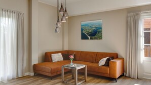 Una sala de estar con un sofá color crema, una mesa de centro de vidrio y un cuadro de un paisaje.
