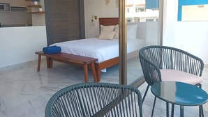 Une chambre à coucher avec un lit, une table de chevet sur laquelle est posée une serviette enroulée, une chaise et une petite table.