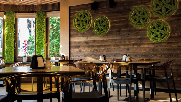 L’intérieur d’un restaurant avec des murs en bois, des décorations murales vertes, ainsi que de nombreuses tables et chaises.