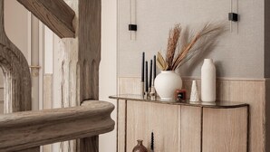Un intérieur moderne avec un escalier en bois, une console agrémentée d’objets décoratifs et un sol à motifs.
