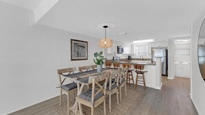 Une cuisine moderne avec des meubles blancs, un îlot central et des appareils électroménagers en acier inoxydable.