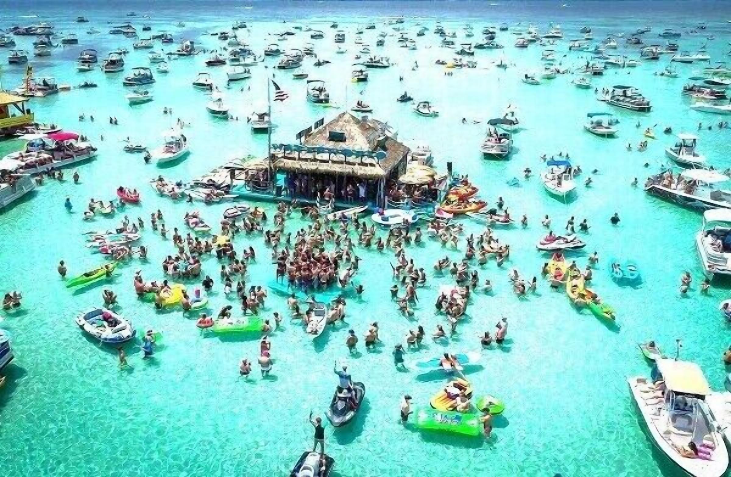 Ein überfüllter Strand mit vielen Booten und Menschen, die das Wasser genießen.