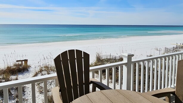 A beach view from a covered deck with a wooden chair and table. - 11A - 1BR $700+ in freebies incl golf, On Beach (Miramar Beach)