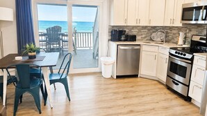 A kitchen with a view of the ocean, a dining area with chairs, and a small table with a plant. - 11A - 1BR $700+ in freebies incl golf, On Beach (Miramar Beach)