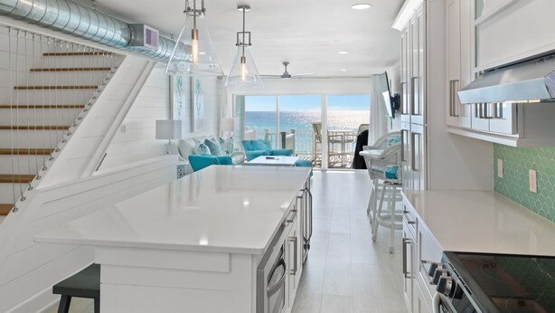 A modern kitchen with white cabinetry, a large island, and a view to the outside. - Miramar Beach 2BR • Beach + Free Beach Setup & Fun (Miramar Beach)