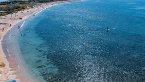 A beach with clear water, a sandy shore, and distant hills.