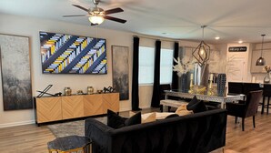A modern living room with a black sofa, a wooden cabinet, and a dining area with a glass table. - Chic Family Home Near All ATL Hotspots (Atlanta)