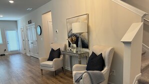 A spacious living room with a high ceiling, a staircase, and a door leading to another room. - Chic Family Home Near All ATL Hotspots (Atlanta)