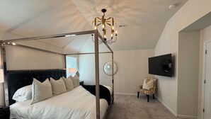 A bedroom with a four-poster bed, a chandelier, a television mounted on the wall, and a chair. - Chic Family Home Near All ATL Hotspots (Atlanta)