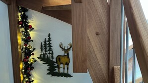A wooden staircase with a wall mural of a deer and trees, and a Christmas garland. - Engel Ingold Lodge-Romantic place in the middle of the Swiss Alps-Hotel Services (Habkern)