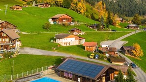 A rural village with traditional wooden houses, a swimming pool, and a road leading through the area. - Engel Ingold Lodge-Romantic place in the middle of the Swiss Alps-Hotel Services (Habkern)