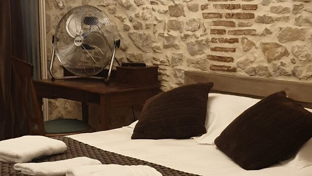 Un lit bien fait, avec une couverture marron, deux oreillers et une serviette blanche.