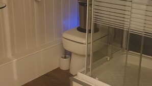 Une salle de bain équipée de toilettes, d’un sèche-mains et d’une cabine de douche en verre.