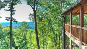 Eine Holzdar Terrasse mit Blick auf eine bewaldete Landschaft und die Berge.