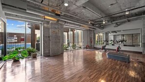 A spacious indoor area with a polished wooden floor, large windows, and exercise equipment. - The Bentley Collection - Downtown Penthouse Close to Convention Center (Dallas)