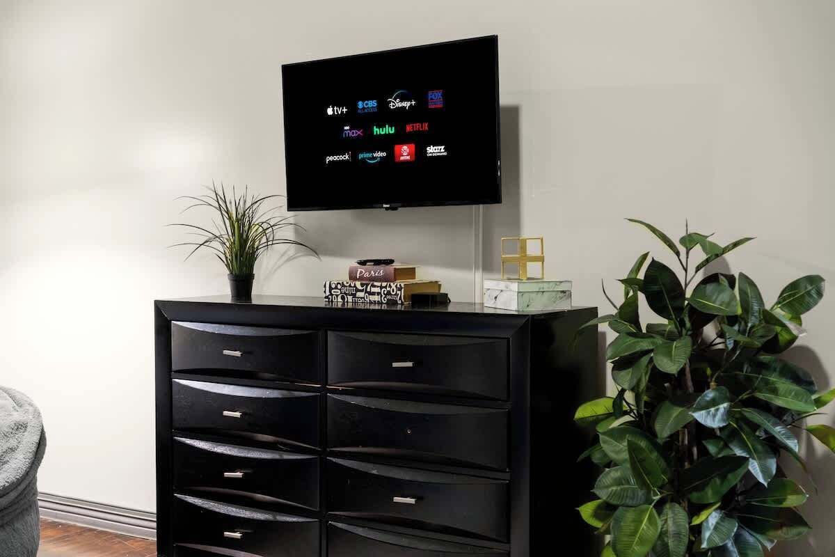 A flat-screen TV mounted on a wall displaying various streaming service logos.