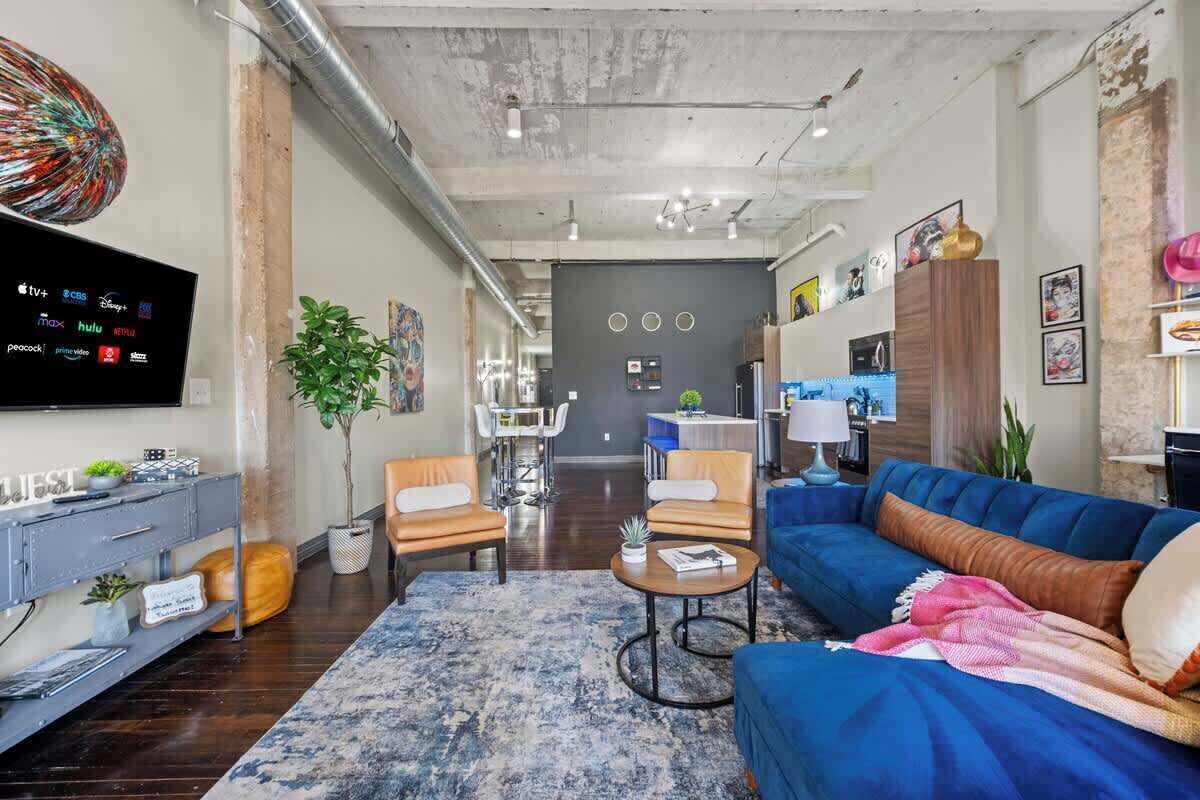 Una sala de estar moderna con un sofá azul, una mesa de centro y un televisor que muestra diversos servicios de transmisión.