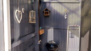 A small, enclosed outdoor space with a wooden fence, a grill, and decorative items like a heart-shaped ornament and a birdhouse. - Cozy and fully furnished apartment centrally located between Enkhuizen and Hoorn (Hem)