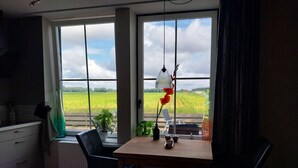 A kitchen with a large window, a table with a lamp, and a chair. - Cozy and fully furnished apartment centrally located between Enkhuizen and Hoorn (Hem)