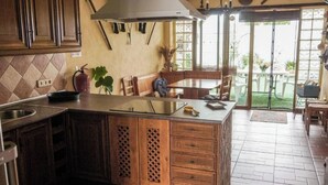 A kitchen with wooden cabinets, a large island, and a dining area with a table and chairs. - Casa Jienense in the Sea of Olives (Pet Friendly) (Campillo del Río)