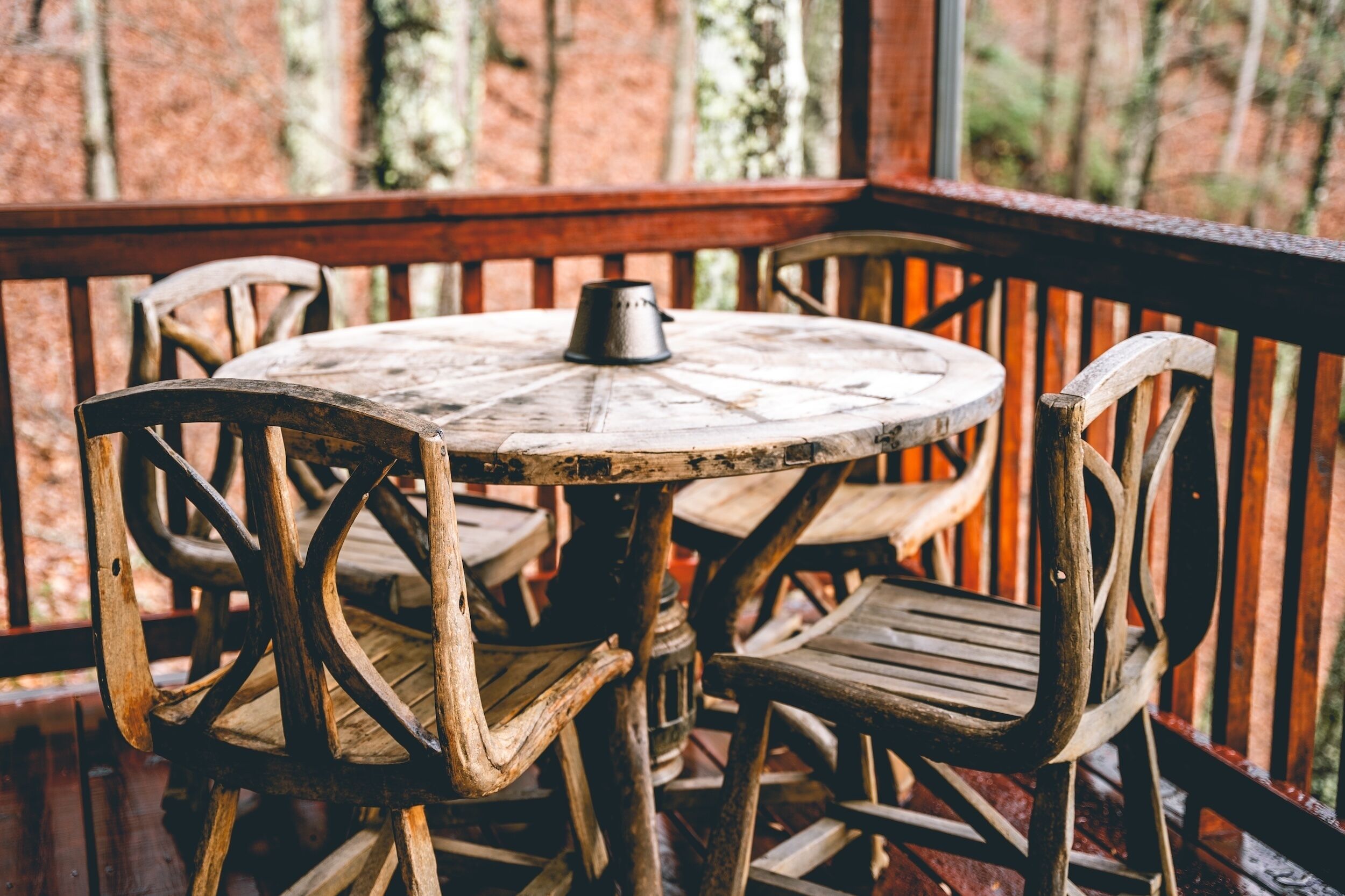 A rustic wooden table with chairs on a wooden deck.
