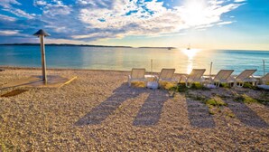 A pebbled beach with sun loungers and a lifeguard tower. - Lovely Flat Just Steps From the Beach (Fazana)
