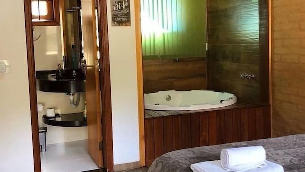 Una habitación de hotel con una cama, un baño con bañera y una puerta de madera.