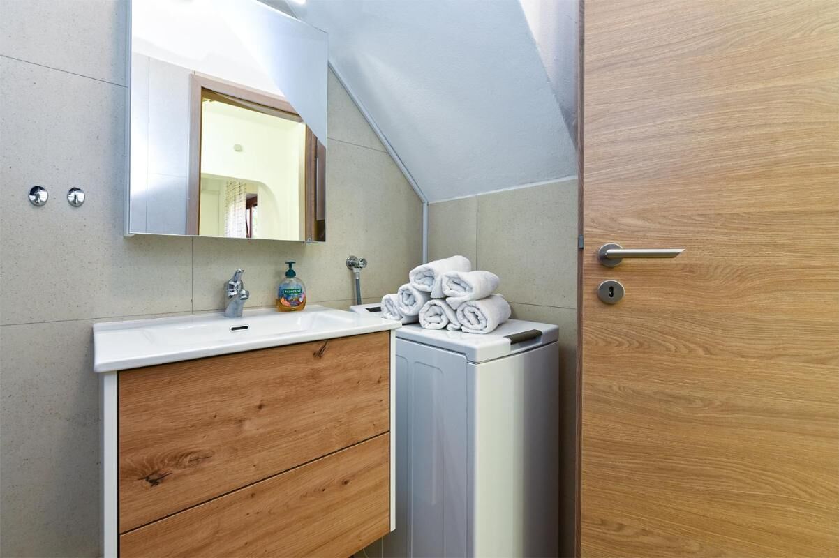 A bathroom with a wooden vanity, a sink, a mirror, and a towel rack.