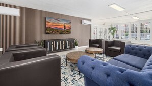Un hall d’entrée moderne avec des canapés en cuir, une table basse en bois et un grand tableau représentant un paysage désertique.