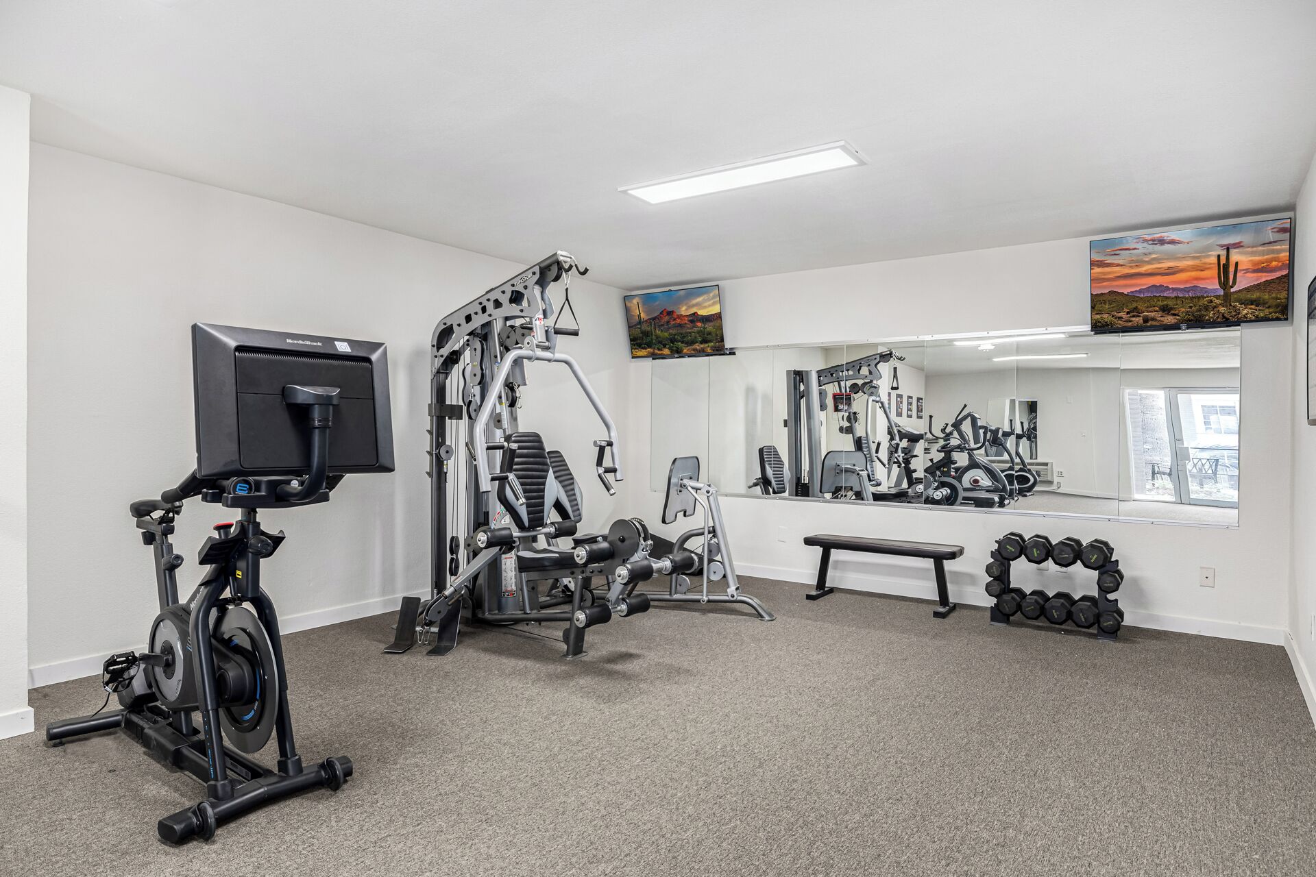 Une salle de sport équipée de machines d’exercice, d’un banc et d’haltères.
