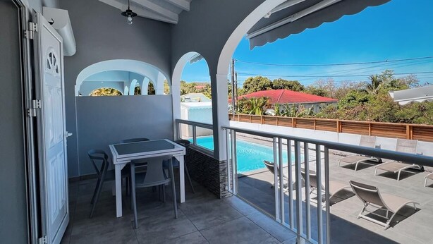 A balcony with a pool, a table, and chairs.