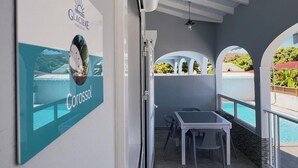 A modern hotel room with a view of a pool and a balcony.