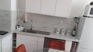 Una cucina moderna con mobili bianchi, un tavolo da pranzo in vetro e sedie rosse.