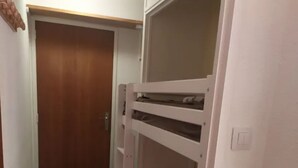 Un corridoio stretto con un letto a castello, una porta di legno e un tappeto blu.
