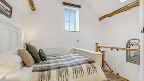 Un dormitorio con cama, radiador, ventana y tragaluz.