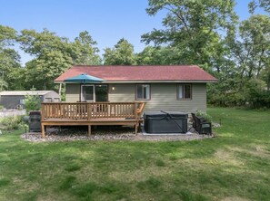 A single-story house with a red roof, a wooden deck, and a black grill. - Peaceful Cabin on Whitefish Chain (Crosslake)