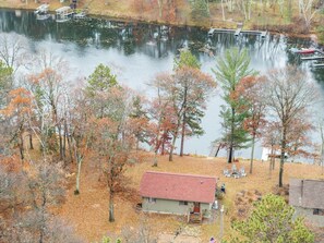 A lakeside cabin with a dock, surrounded by trees with autumn foliage.