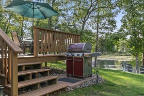 A deck with outdoor seating, a grill, and a view of a lake. - Peaceful Cabin on Whitefish Chain (Crosslake)