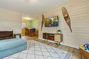 A room with a bed, a TV, a dining area, and a wall-mounted shelf. - Peaceful Cabin on Whitefish Chain (Crosslake)
