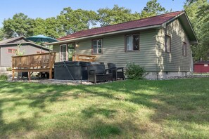 A single-story cabin with a fenced deck, outdoor seating, and a hot tub.