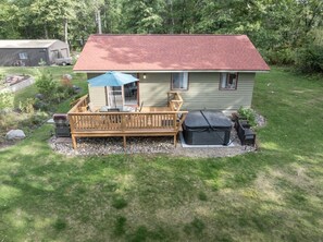 A single-story house with a red roof, a wooden deck, and a covered patio area. - Peaceful Cabin on Whitefish Chain (Crosslake)